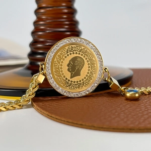 Macro shot of gold coin bracelet with portrait relief, white zircons and evil eye charm