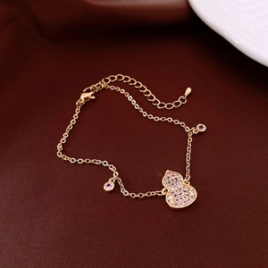 Detailed macro view of gold-plated gourd pendant bracelet with pink and white cubic zirconia