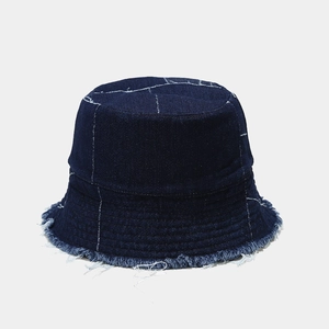 Detail of blue denim bucket hat with white grid stitching and frayed distressed edges