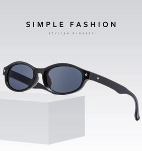 Détail de lunettes de soleil ovales noires à monture épaisse sur support minimaliste