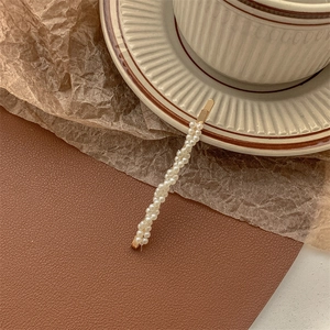 Close-up of elegant double-row pearl hair clip on vintage background with gold metal base