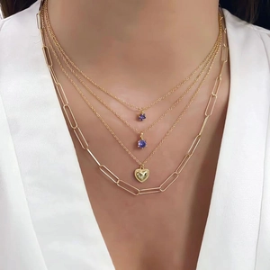 Layered gold necklace set with purple gemstone and heart pendants on a female model