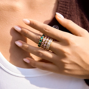 Close-up of gold rings set with pink and green zircons worn on model fingers
