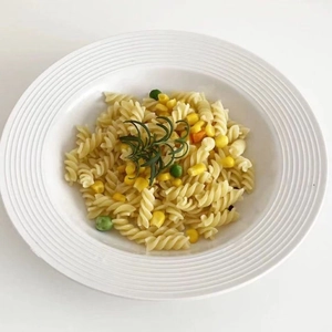 Detail of white ceramic rimmed soup plate with ribbed texture holding pasta