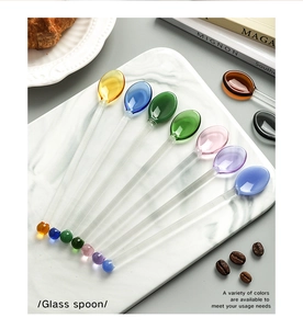 Detailed view of colorful glass stir spoons with heart-shaped heads on white marble tray