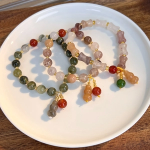 Macro view of colorful agate beaded bracelets with jade gourd charm and golden accents