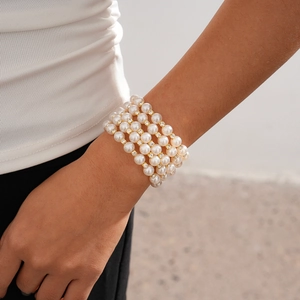 Close-up of elegant four-layer baroque pearl bracelet with gold diamond-encrusted spacers