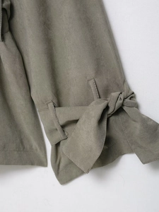 Detailed close-up of olive green faux suede sleeve cuffs with elegant tie-up bow design
