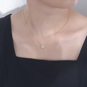 Close-up of a delicate gold snowflake necklace with sparkling stones on a woman's neck