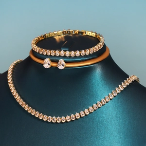 Macro view of gold teardrop zircon jewelry set featuring a necklace, bracelet and earrings