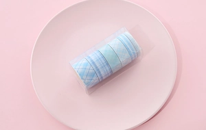 Blue grid washi tape set in clear box displayed on a pink plate for DIY journals
