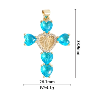 Détail du pendentif croix dorée avec pierres de cœur bleues et mesures de taille