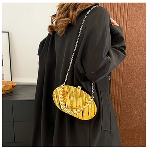 Detailed view of a gold shell-shaped clutch bag with wavy texture and beaded chain