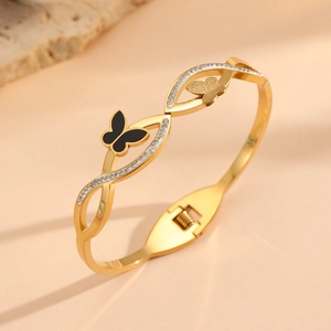 Détail d'un bracelet doré 18 carats avec papillon noir émaillé et cristaux scintillants