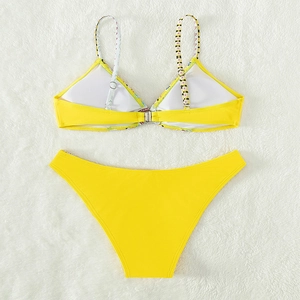 Bright yellow two-piece bikini swimsuit with metal back clasp on white plush backdrop