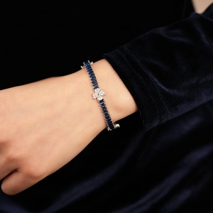 Close-up of elegant zircon clover bracelet with blue gemstones on female wrist