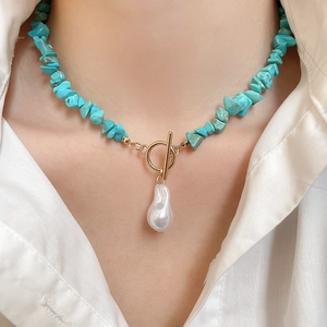 Detail showing turquoise beaded necklace with baroque pearl pendant and gold T-bar clasp