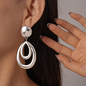 Silver metallic teardrop earrings with a smooth polished finish on a female model