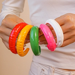 Dettaglio di bracciali in acrilico colorato in rosso, giallo, verde, rosa e bianco