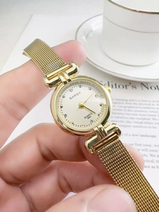 Close-up of golden vintage quartz watch with diamond dial and mesh metal strap on wrist