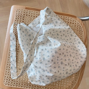 Détail du sac cabas en coton à fleurs sur une chaise avec un motif floral bleu clair