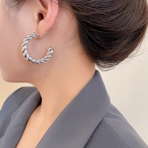 Close-up of silver twist hoop earring worn by a model in professional grey suit
