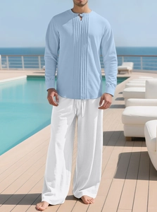 Herren-Set aus hellblauem Baumwoll-Leinen-Hemd und weißer Hose auf einer Resort-Terrasse