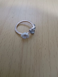 Macro shot of a silver branch ring featuring a white flower and two clear gemstones on wood