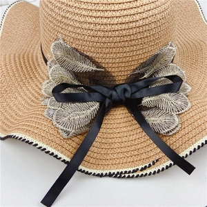 Detailed view of women's straw sun hat with black satin bow and beige leaf embroidery