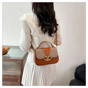 Detail of brown crossbody bag featuring herringbone fabric patchwork and gold metal buckle