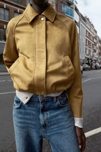 Detail of tan faux suede cropped baseball jacket with collar and metallic snap buttons