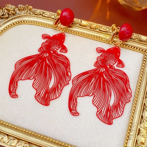 Gros plan de boucles d'oreilles clips poisson rouge sur un plateau doré vintage