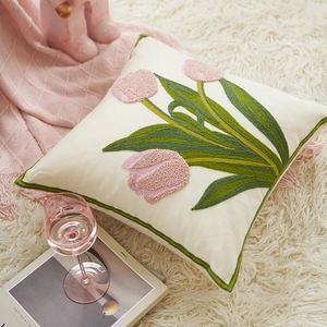 Nordic square beige pillow with pink tulip embroidery and green piping on soft rug