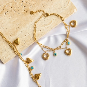 Golden double-layer bracelet with heart charms and evil eye beads on silk fabric