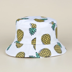 Détail du chapeau bob blanc avec imprimé ananas jaune et motif de feuilles tropicales