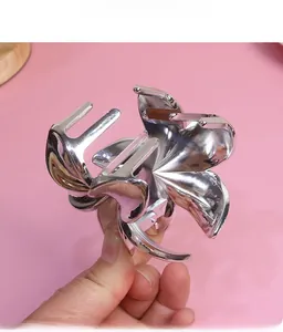 Detail of silver metallic flower hair claw clip with polished finish on pink background