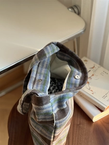 Vue détaillée du fermoir magnétique et de la texture en laine à carreaux de ce sac cabas