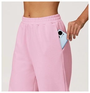 Detail of pink high-waisted sweatpants showing side pocket with a phone for storage