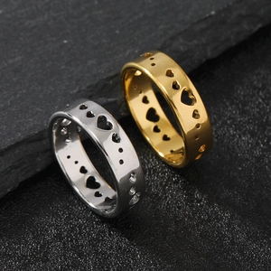 Close-up of gold and silver stainless steel rings with cut-out heart patterns on dark rock