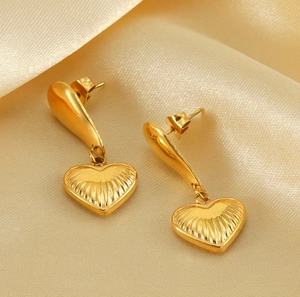Detailed macro view of heart-shaped gold earrings with radiant texture on silk background