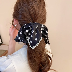 Detail of floral scrunchie with white pearls on a black bow tied on a ponytail