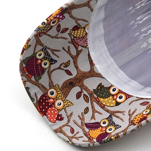 Detailed close-up of vibrant owl print and canvas texture on baseball cap visor