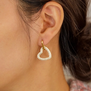 Elegant gold heart hoop earrings with sparkling crystal pavé worn by a female model