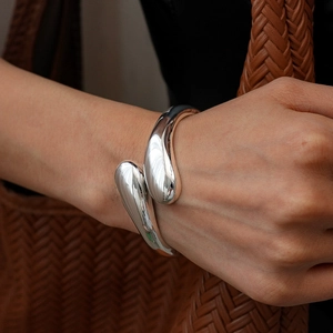 Close-up of silver water drop open cuff bracelet showing liquid metal texture and glossy finish
