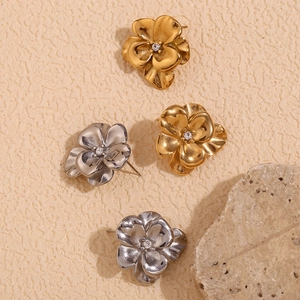 Macro detail of 18K gold and silver floral stud earrings with inlaid zircon crystals