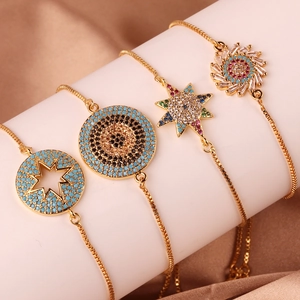 Gold plated evil eye and geometric bracelets with colorful zircons on silk background