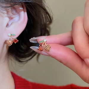 Macro detail of red cherry stud earrings with inlaid zircon rhinestones and gold plating