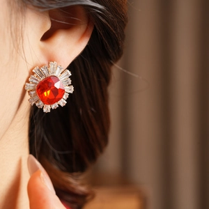 Close-up of elegant red stone stud earrings with radiating crystal halo on ear