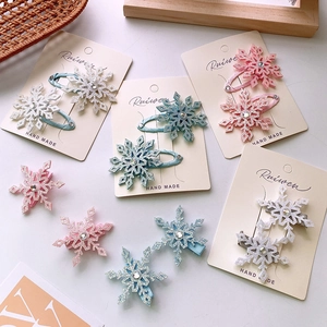 Close-up of snowflake hair clips with glitter coating and rhinestones on card