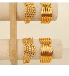 Detail shot of wavy gold open bangles with high-polish finish on jewelry display stand